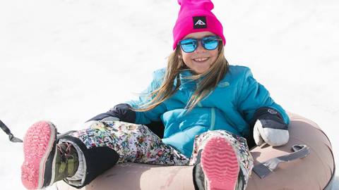 Happy little girl smiles while sitting in a snow tube. 