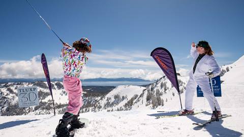 A skier and a snowboarder play snow golf at Alpine on a sunny day.