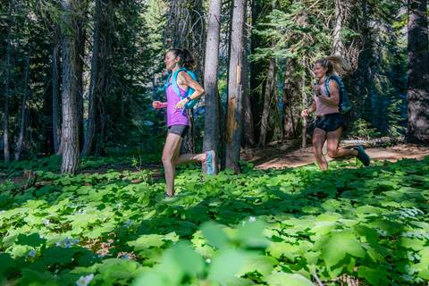 two girls running though beautiful sierra mountains