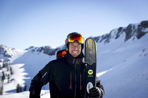 Johnny Moseley with his skis on a blue bird day