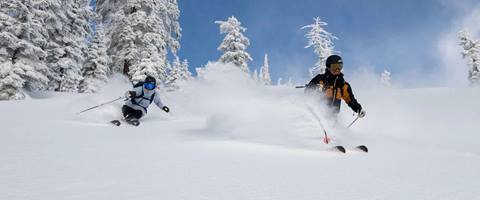 Two skiers ride Alpine on a powder day at Palisades Tahoe. 