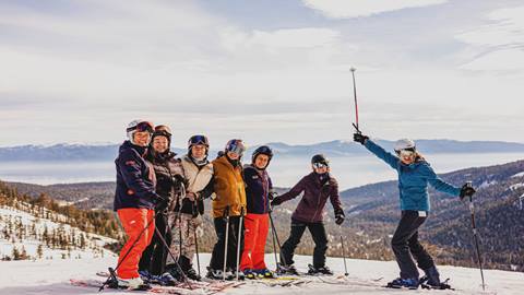 Happy adults in a ski lesson at the top of a Palisades Tahoe mountain.