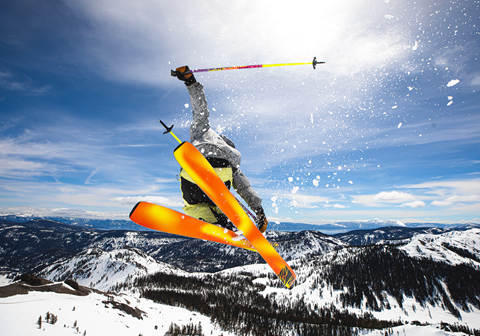 Skier with bright skis jumping with backdrop of Lake Tahoe