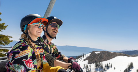 Two people smile on the chairlift