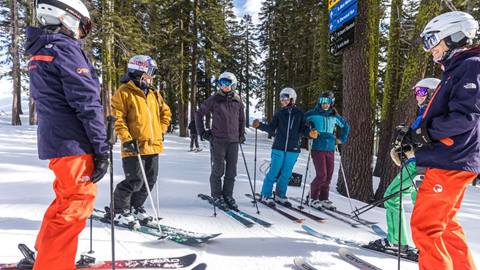 Women of Winter camp talking while in their skis at a lift sign at Alpine.