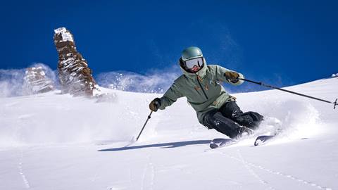 Advanced skier skis down mountain in powder.