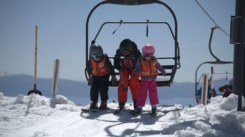 Two kids getting off the chairlift with a Mountain Sports School instructor at Palisades Tahoe. 