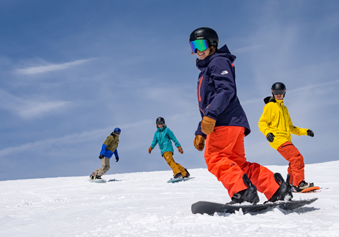 Three snowboarders learning with an instructor on the mountain