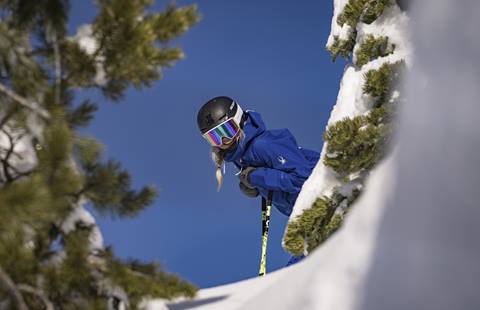 Amie smiling through the snow covered trees on a bluebird day