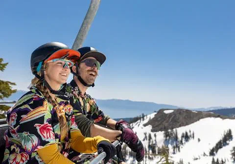 Two snowboarders on chairlift smiling