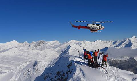 Helicopter dropping off CMH skiers at the peak of a mountain