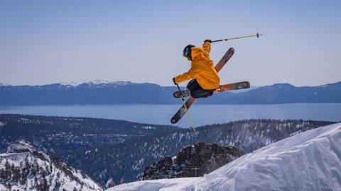 A skier hucking into the air with Lake Tahoe in the background. 