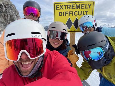 Snowboarders taking a photo with a double black diamond sign