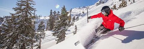 Skier in a red jacket on a bluebird powder day at Palisades Tahoe