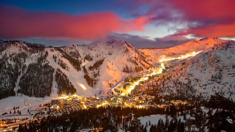 Sunset over Palisades Tahoe in winter with the village lit up