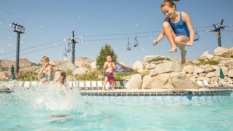 Kids jumping and doing cannonballs into the High Camp pool in the summer